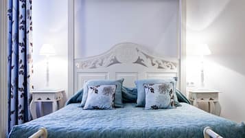 A bedroom with a bed, floral-patterned pillows, a white headboard, and two bedside tables with lamps.