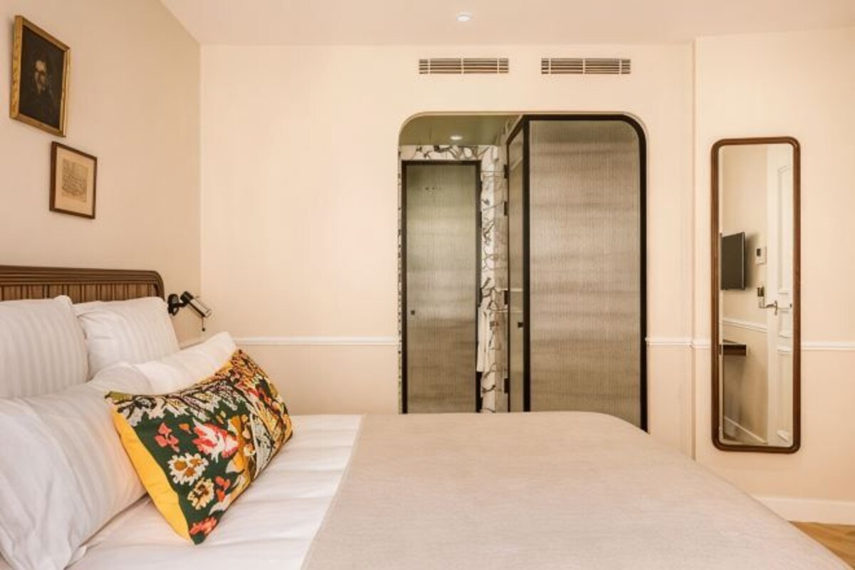 Una habitación de hotel con una cama, un espejo, un armario y una puerta.