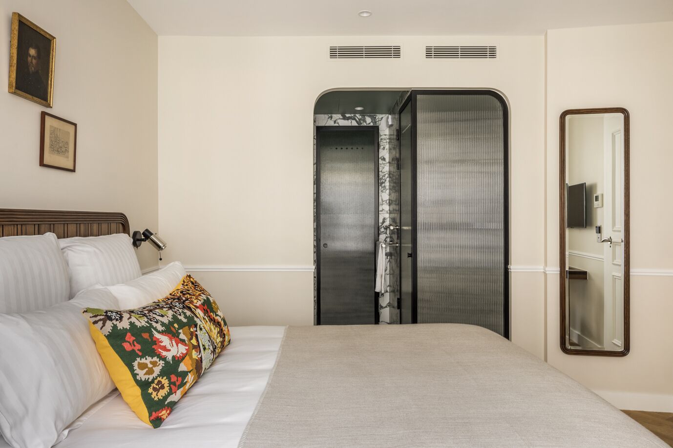 Una habitación de hotel con una cama, un espejo grande y un armario con puerta corredera.
