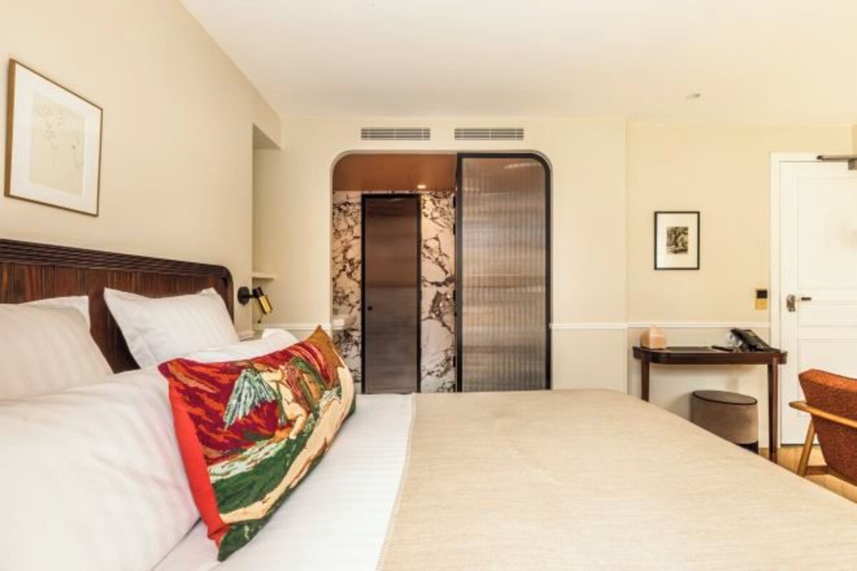 Una habitación de hotel con cama, escritorio, silla y ascensor.