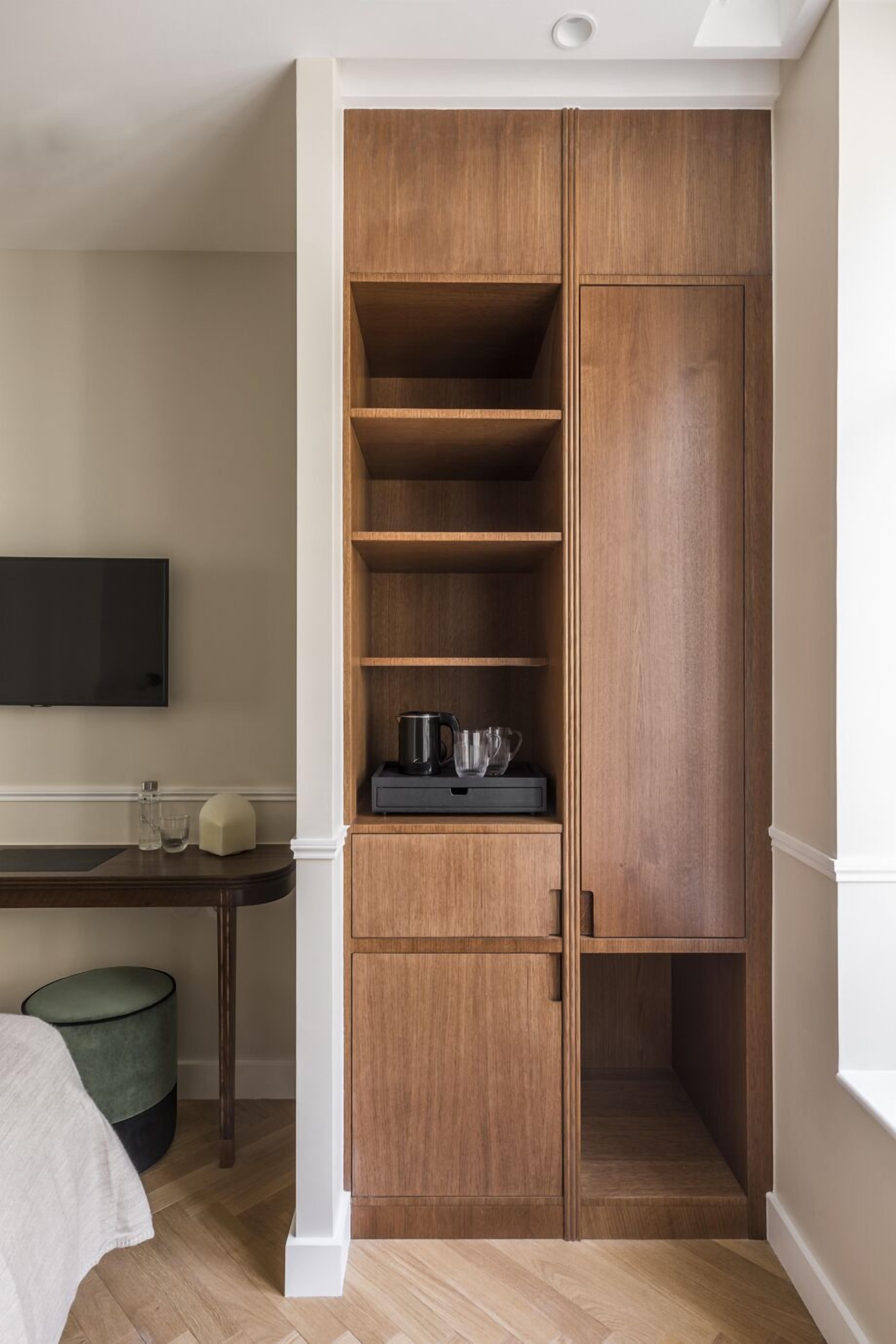 A wooden wardrobe with multiple shelves and a flat-screen TV mounted on the wall.