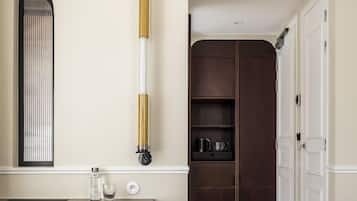 Un dormitorio con cama, mesita de noche, espejo, armario y un taburete pequeño.