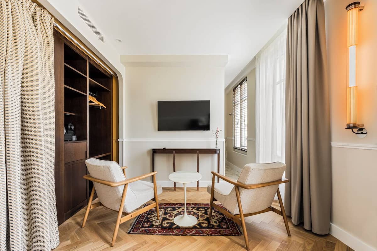 A modern living room with a TV, two armchairs, a small table, and a patterned rug.