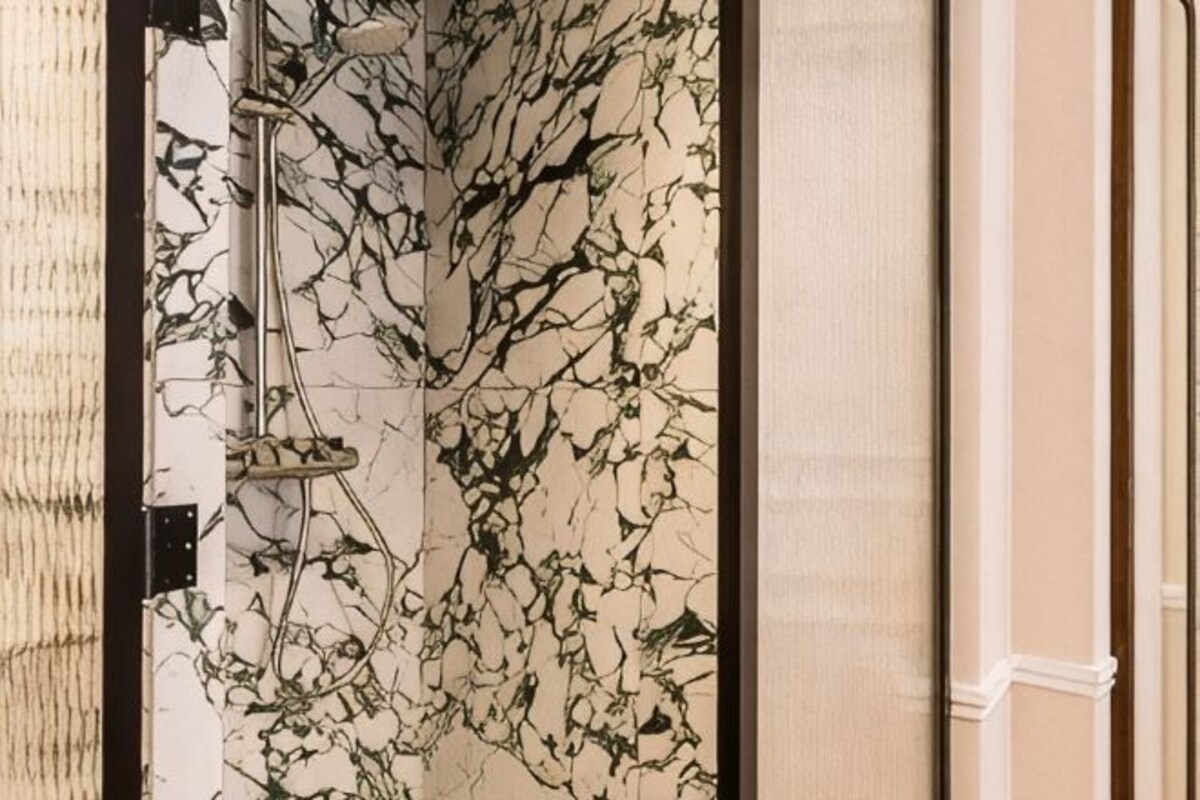 Un baño con pared de mármol, ducha y toallero.