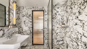 Une salle de bain avec un sol en marbre, un lavabo et un espace douche.