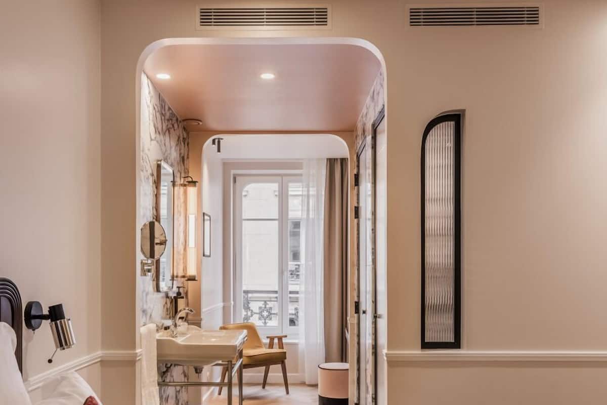 A hotel room with a bed, a desk, a chair, and a bathroom.