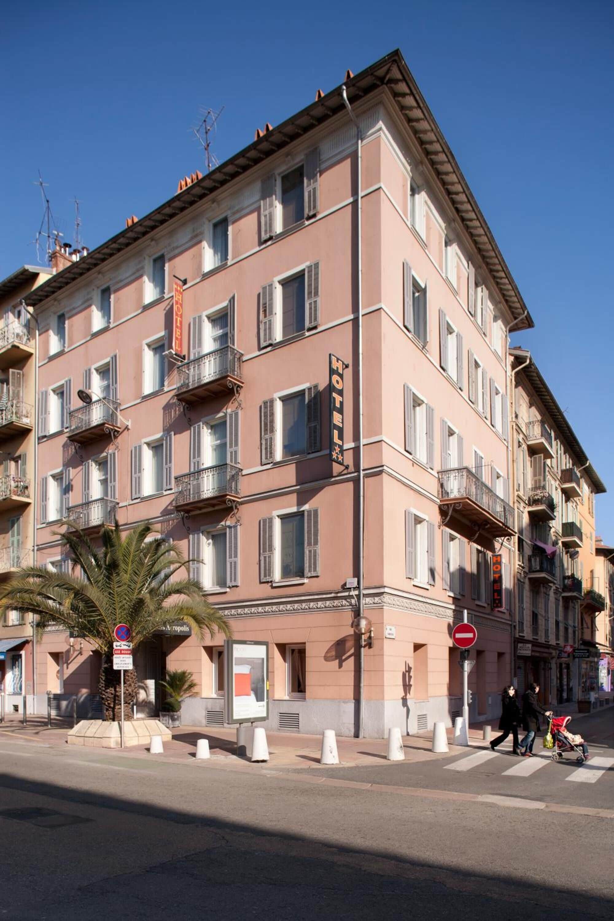 A multi-story hotel with balconies, a sign indicating it is a hotel, and a pedestrian crossing.
