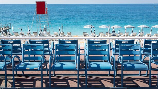 A beachside seating area with blue chairs and striped umbrellas, overlooking the ocean. - Relais Acropolis (Nice)
