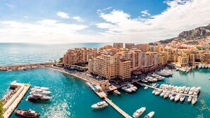 A marina with numerous boats docked, surrounded by multi-story buildings with balconies overlooking the water. - Relais Acropolis (Nice)