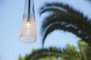 Una lámpara colgante con un diseño cilíndrico transparente sobre un cielo despejado.