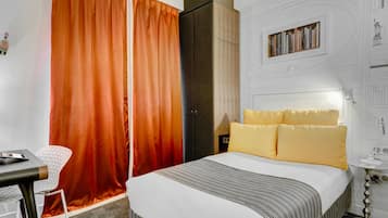 A hotel room with a bed, a desk, a chair, and a wardrobe.
