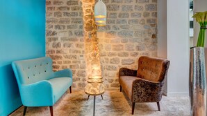 A room with a stone wall, a blue armchair, a brown armchair, and a unique spiral light fixture.