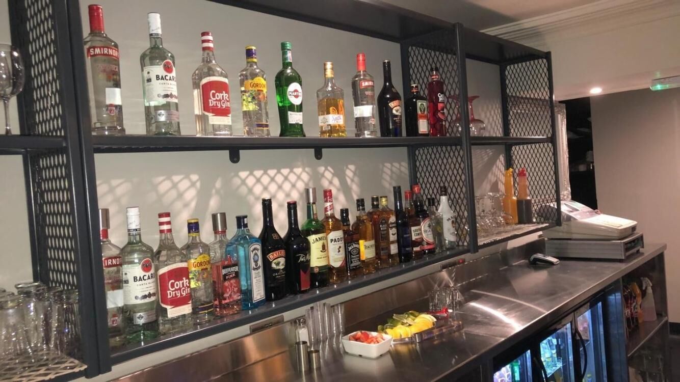 A bar area with shelves of various liquor bottles and glasses.