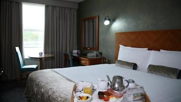 A hotel room with a bed, breakfast tray, newspaper, and a view of the outdoors.