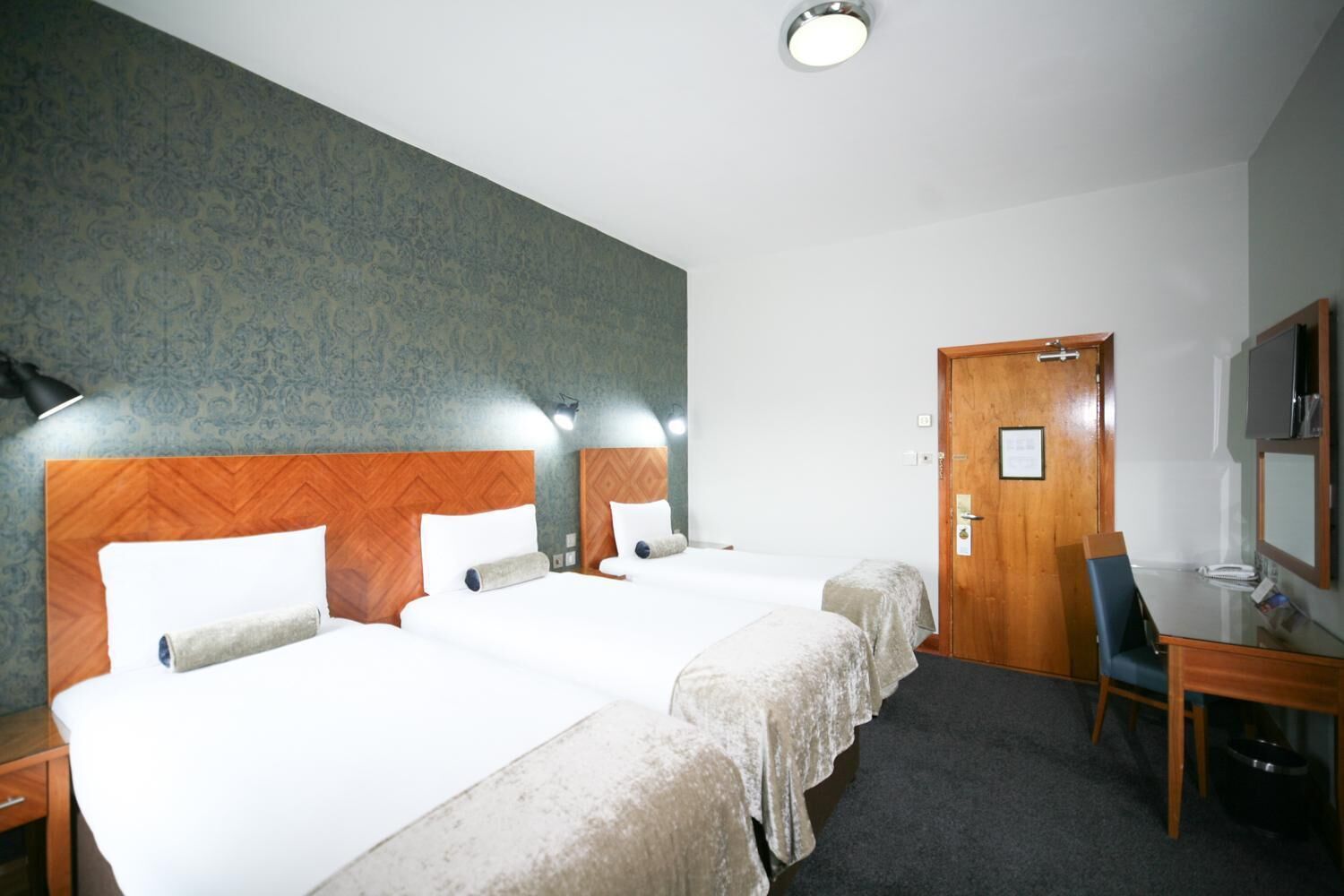 Habitación de hotel con dos camas, un escritorio, una silla y un televisor.