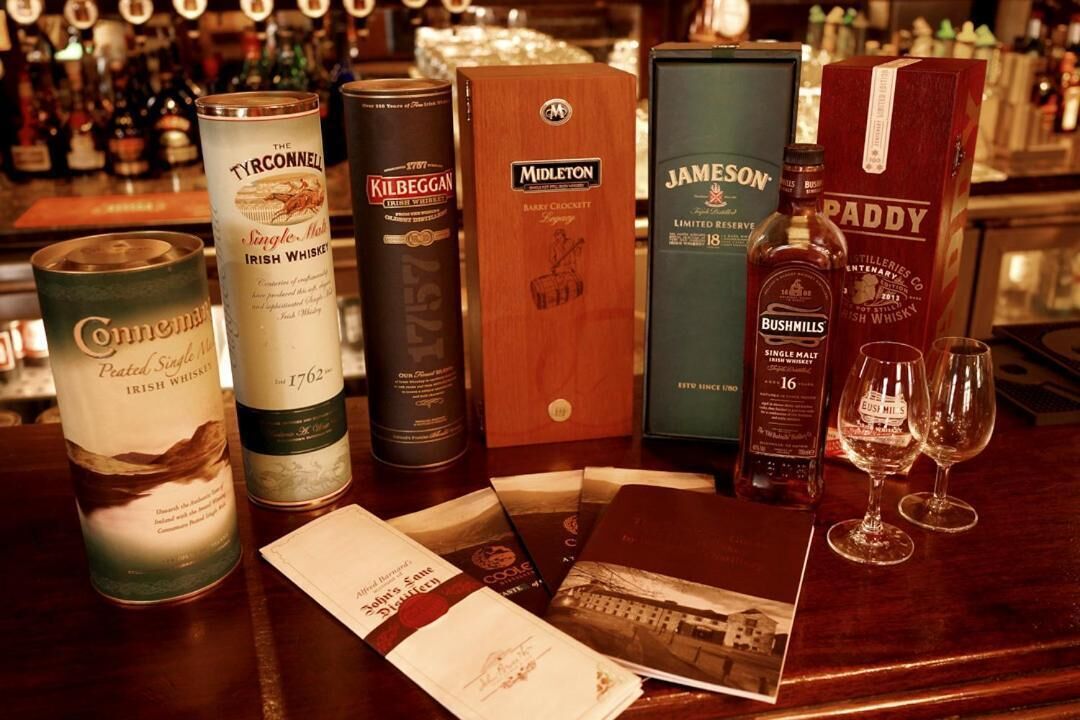 Varias botellas y cajas de whisky sobre una barra.