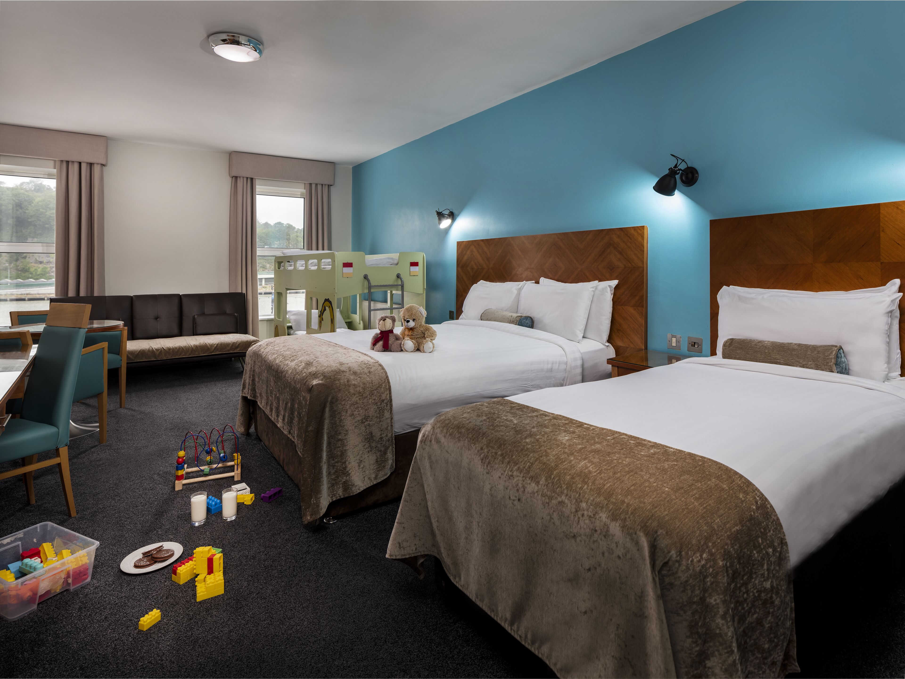 Une chambre d’hôtel avec deux lits, un canapé, un bureau et une fenêtre avec des rideaux.