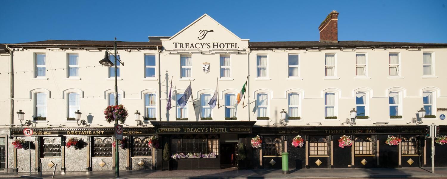 A building with a sign reading "TREACY'S HOTEL" and a restaurant named "TIMBER TOE'S BAR" below it.
