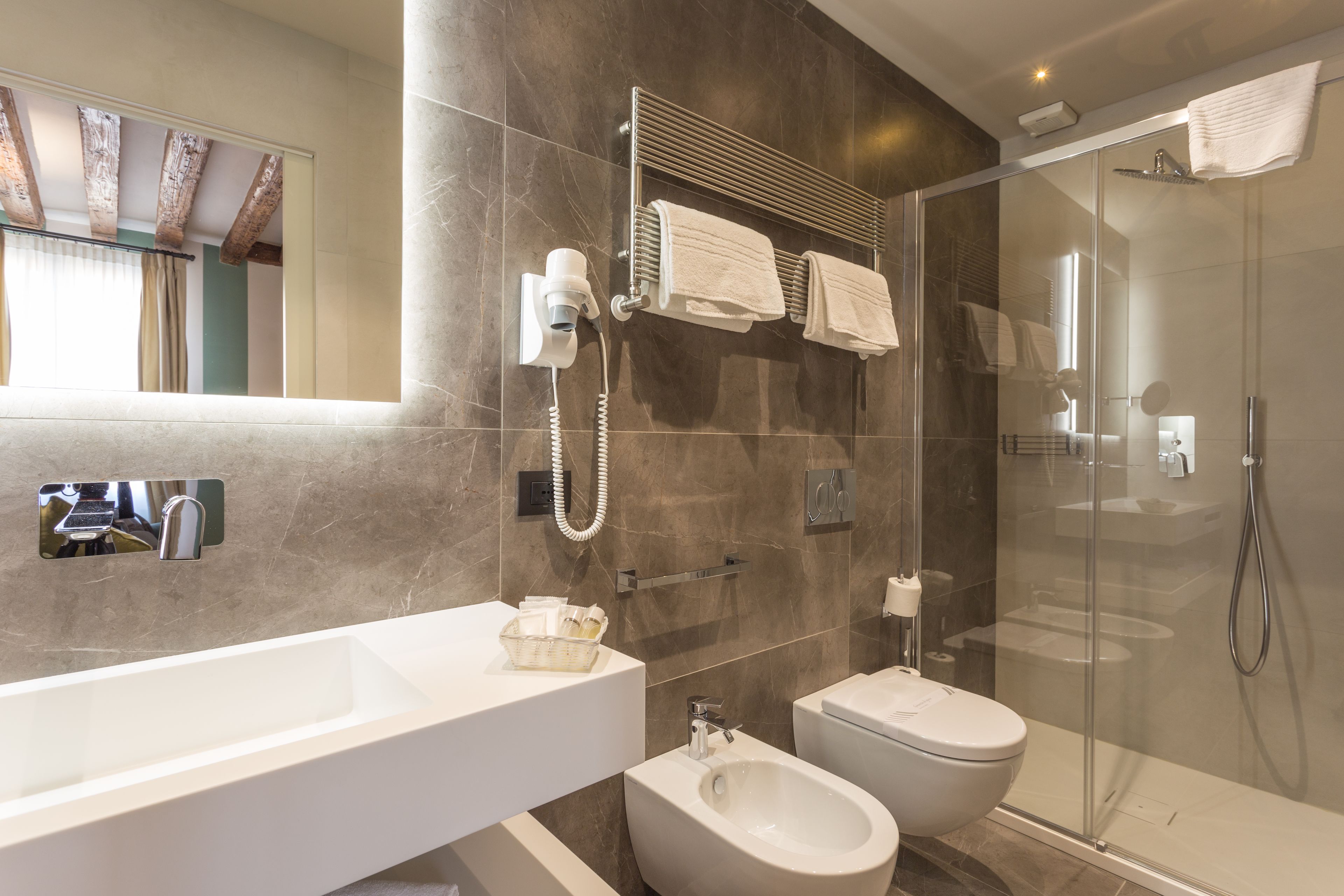 Un baño moderno con un lavamanos grande, un bidé y una ducha con mampara de vidrio.