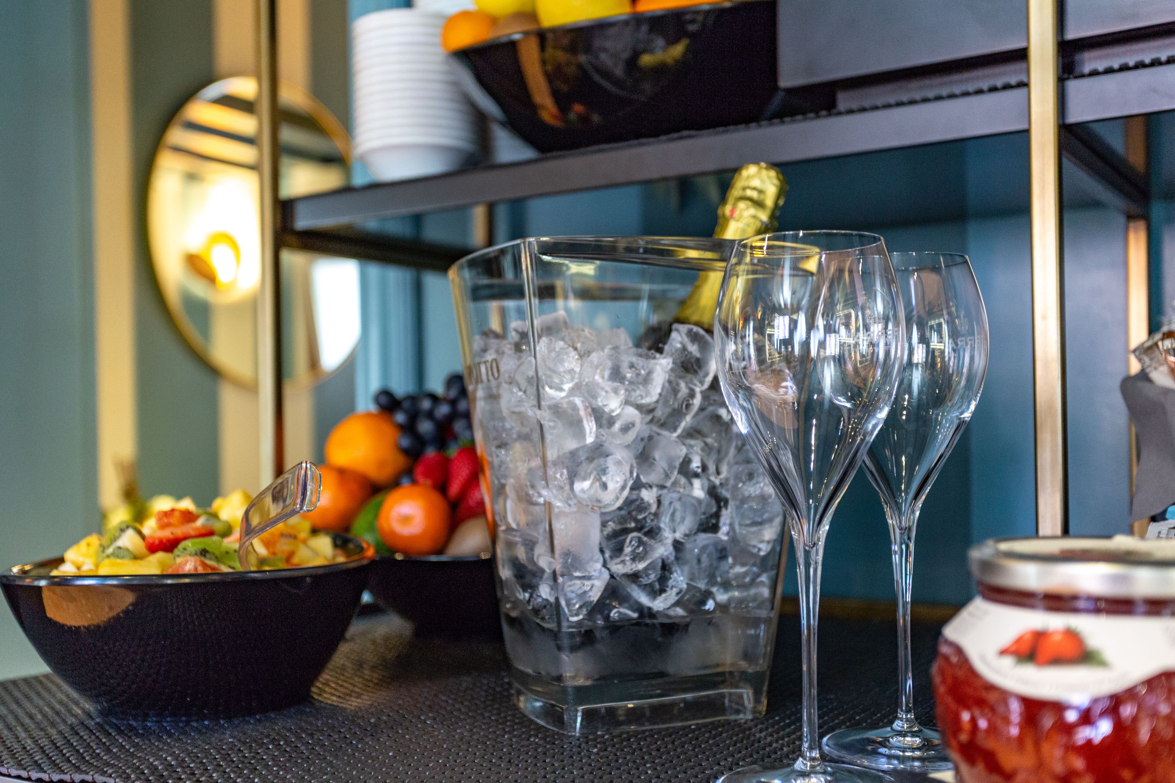 A bar area with a fruit bowl, a pitcher of ice water, and two wine glasses.