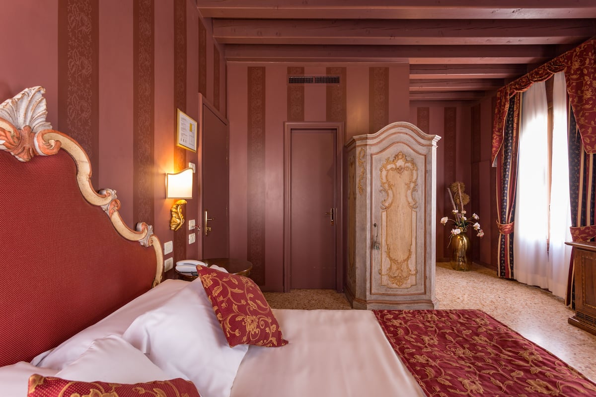 A hotel room with a large bed, a wardrobe, and a mirror.
