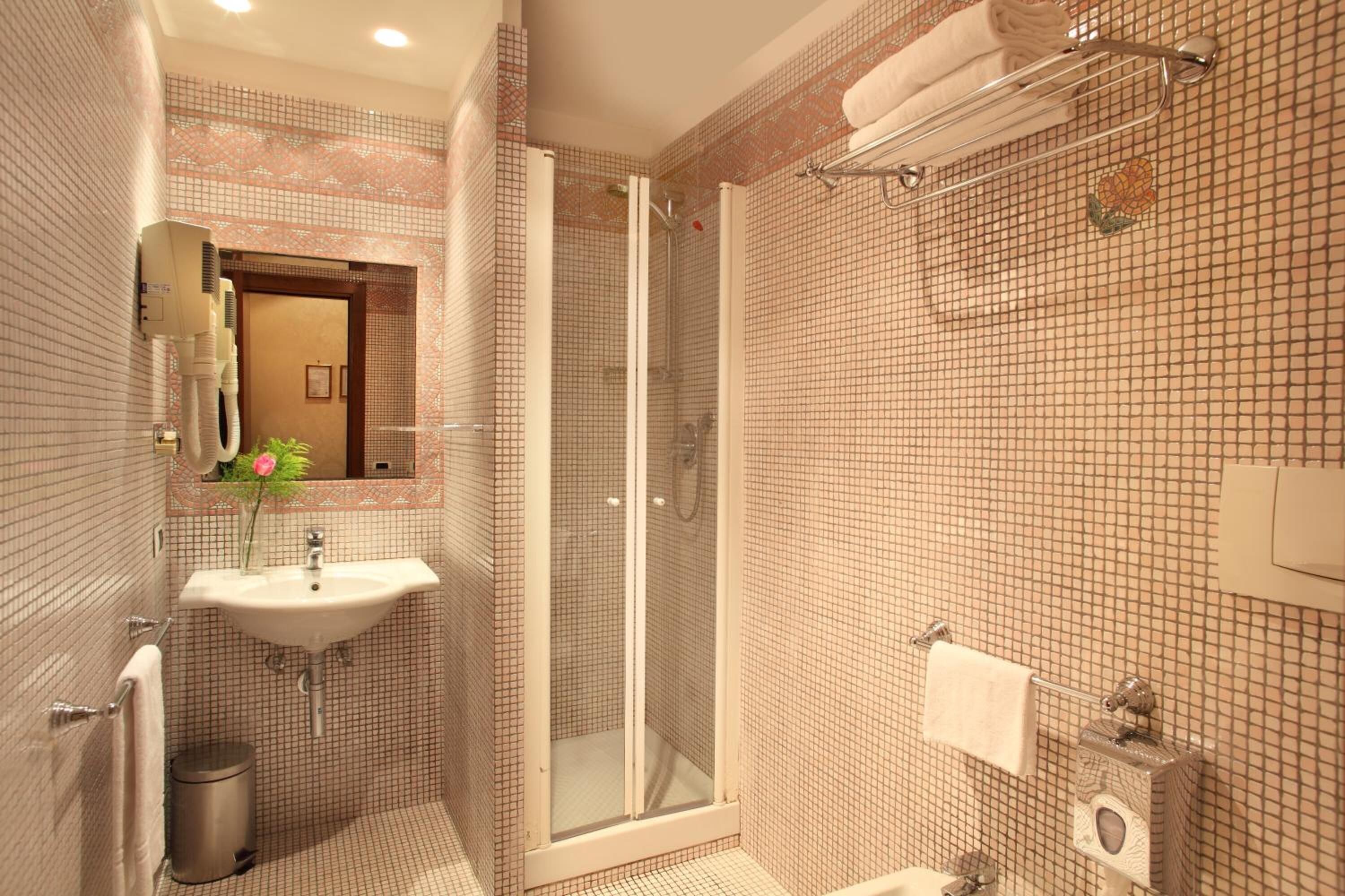Une salle de bain avec un lavabo, un miroir, une douche et des murs carrelés.