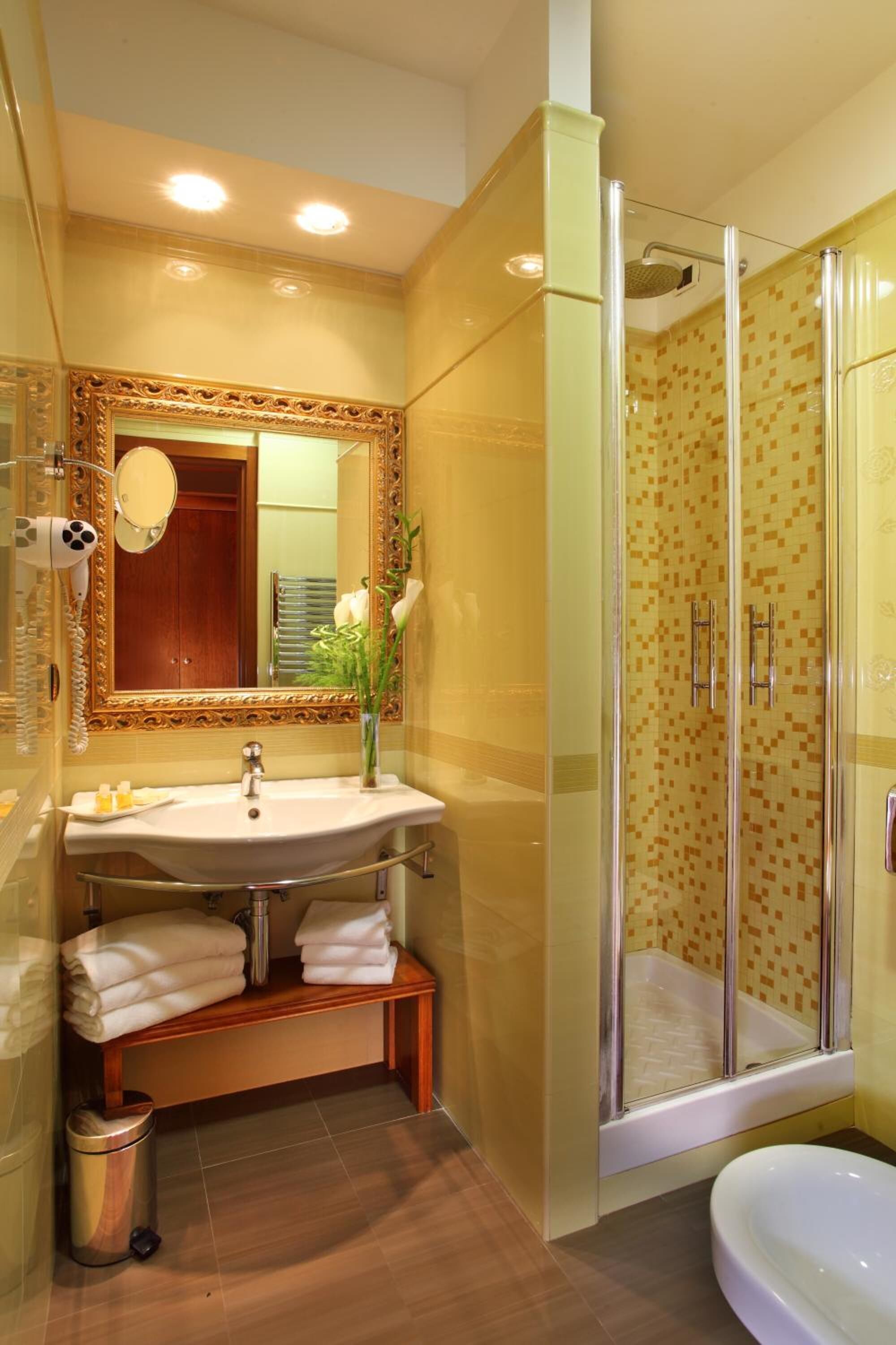 A bathroom with a sink, mirror, and shower.