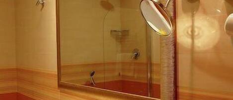 A bathroom with a large mirror, a sink with toiletries, and a shower.