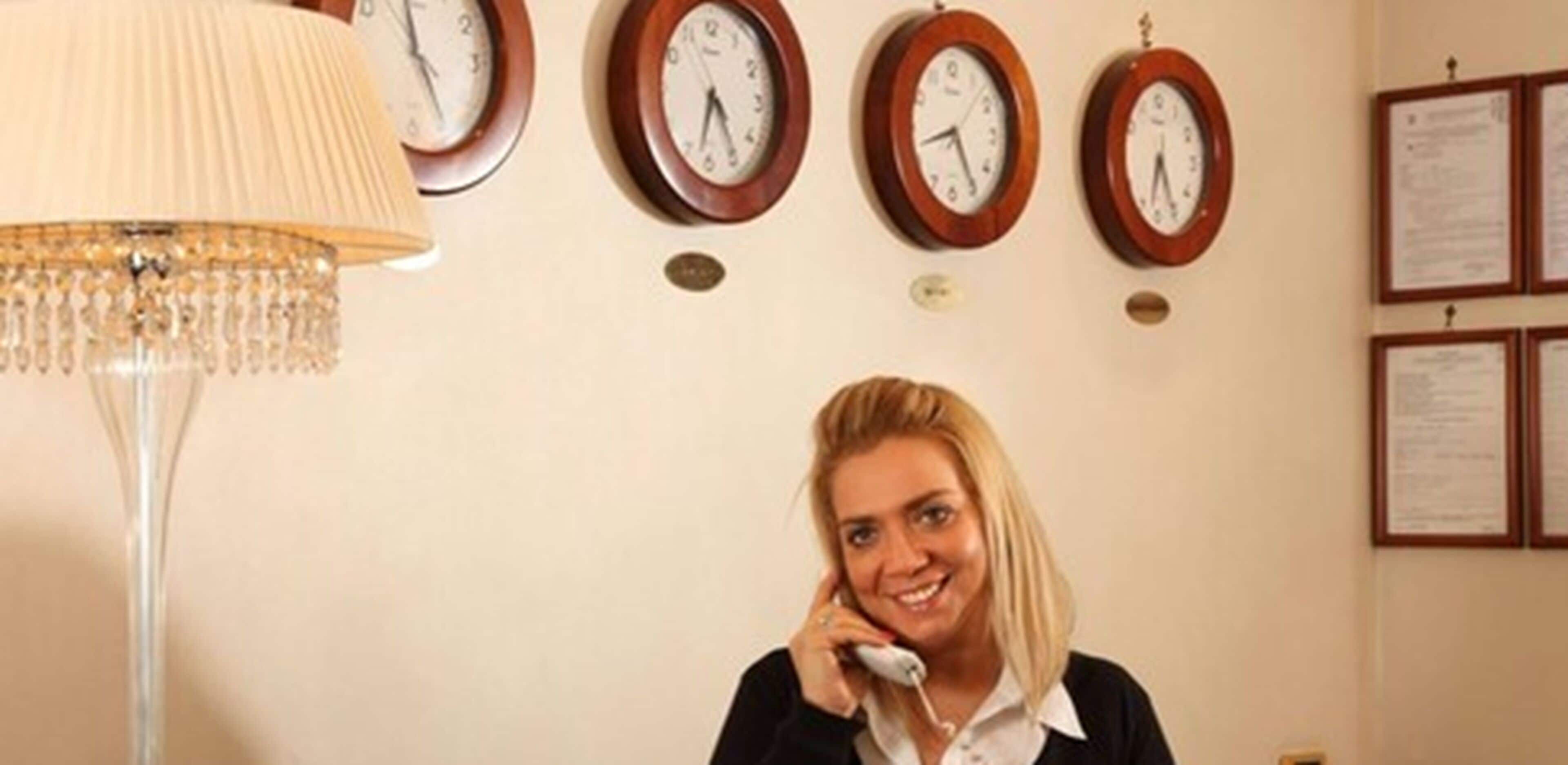 A reception area with a chandelier, multiple wall clocks, and framed documents on the wall.