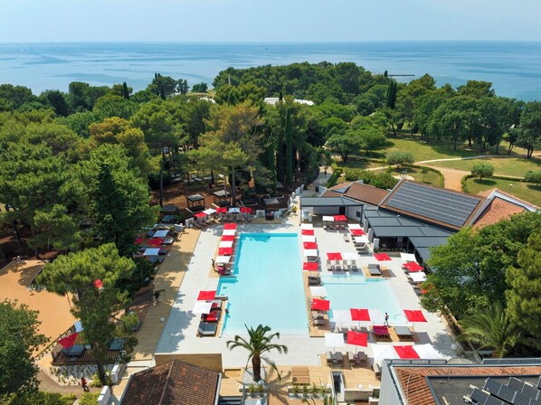 Un resort con piscina, tumbonas y vistas al mar.