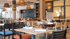 A restaurant with multiple tables, chairs, and hanging wicker lamps. - Hotel Pelegrin Plava Laguna (Umag)