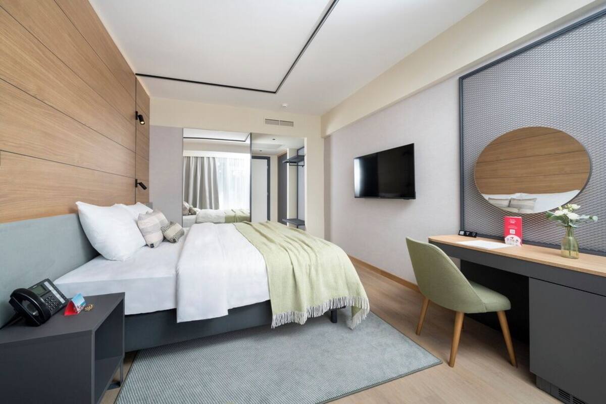 Una habitación de hotel moderna con cama, escritorio y televisión.