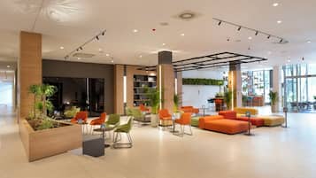 Un vestíbul modern amb zones d'estar, una recepció i una finestra gran.