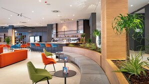 A modern bar area with seating, a bar counter, and shelves with bottles. - Hotel Pelegrin Plava Laguna (Umag)