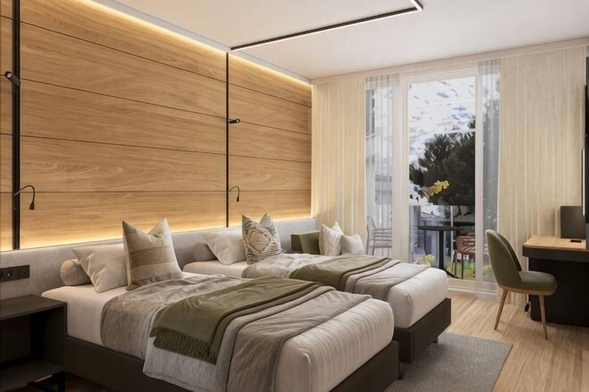 Una habitación de hotel moderna con dos camas, un escritorio y vistas al exterior.