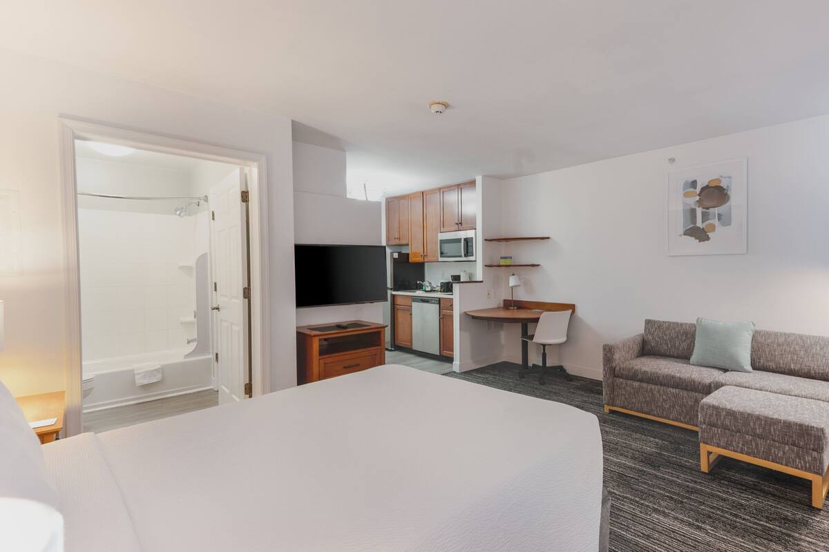 Une chambre d’hôtel équipée d’un lit, d’une télévision, d’une kitchenette et d’une salle de bain.