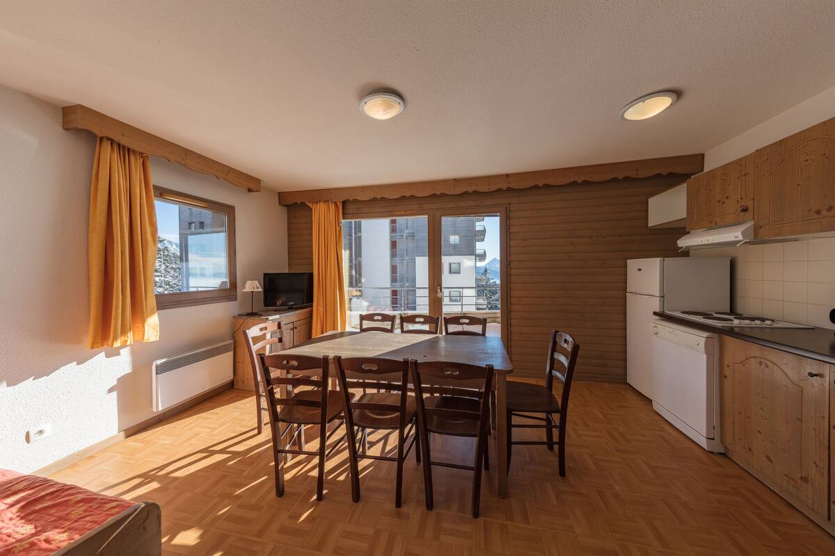 Una cocina compacta con una mesa de comedor, sillas, estufa y refrigerador.
