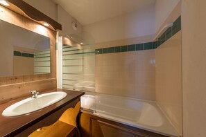 A bathroom with a wooden vanity, a white sink, and a bathtub. - Noemys L'Ecrin des Neiges (Chamrousse)