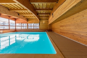 An indoor swimming pool with wooden walls and ceiling, large windows, and a tiled floor. - Noemys L'Ecrin des Neiges (Chamrousse)