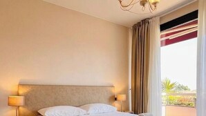 A hotel room with a large bed, two bedside lamps, a chandelier, and a view of the outdoors. - Il Sogno Apartments (Desenzano del Garda)