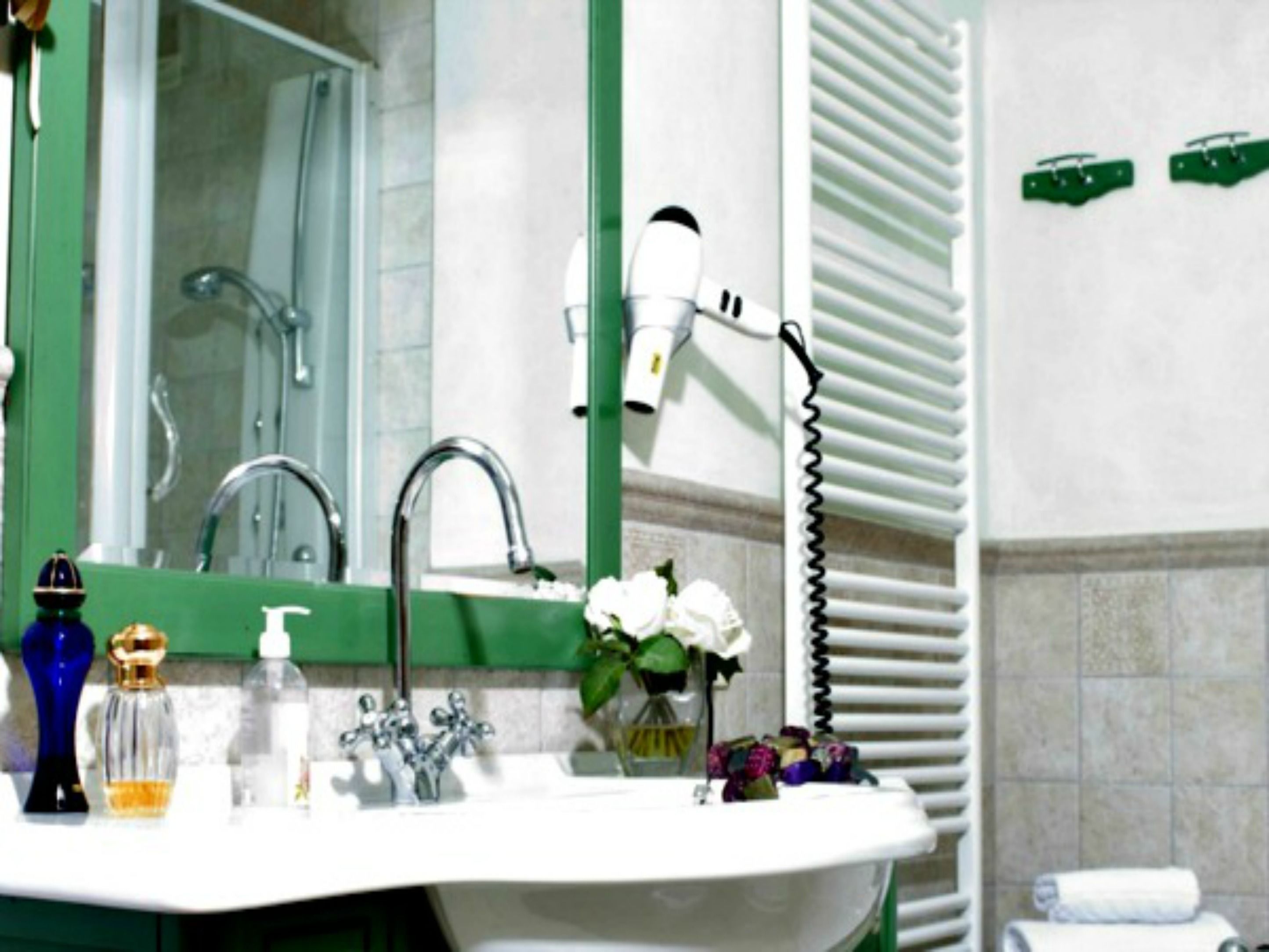 Une salle de bain avec un lavabo blanc, un miroir, un sèche-cheveux et un porte-serviettes.