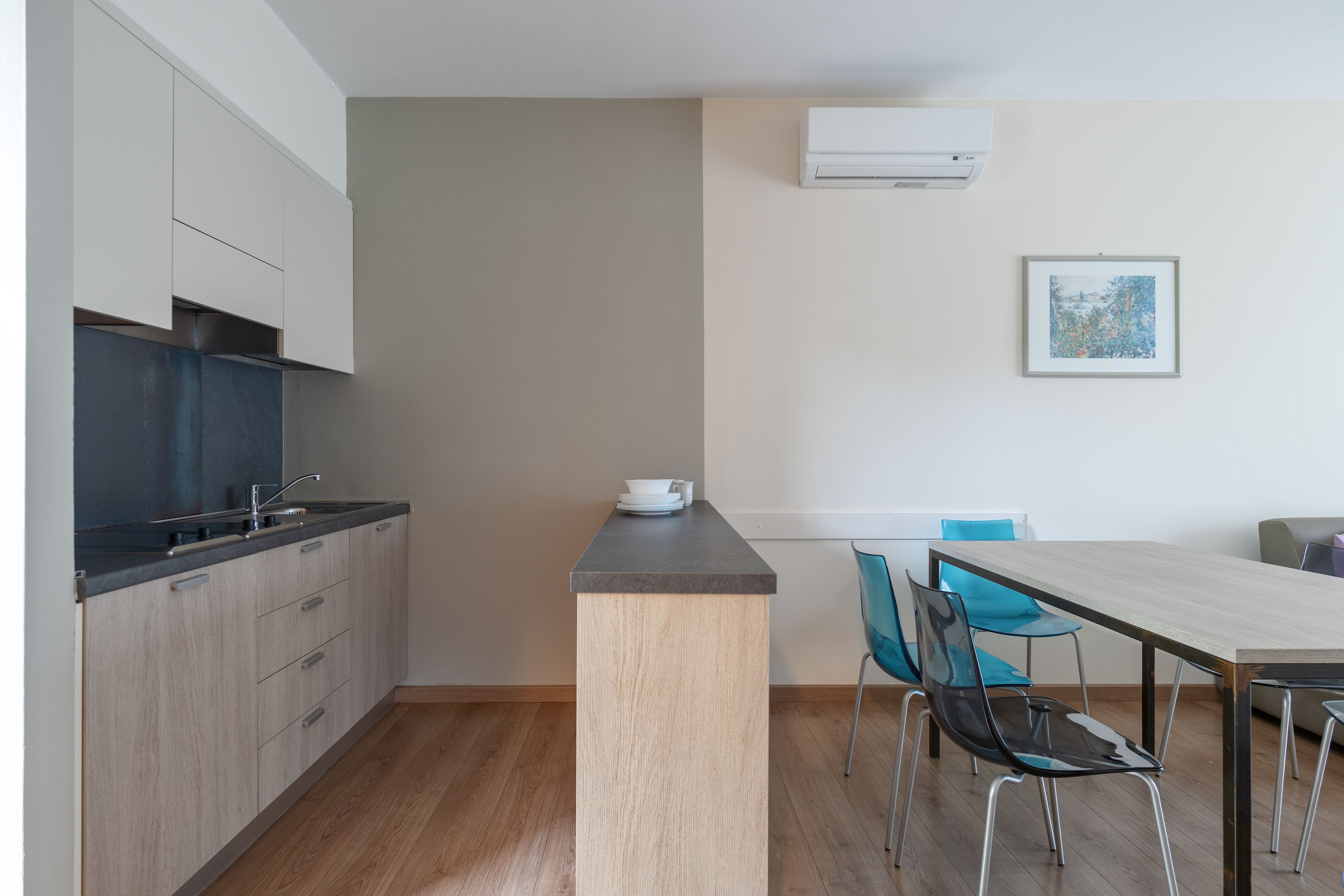 A modern kitchen with a wooden countertop, a sink, and cabinets. There is a dining area with a table and chairs.