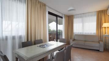 A room with a dining table, chairs, a sofa, and a lamp.