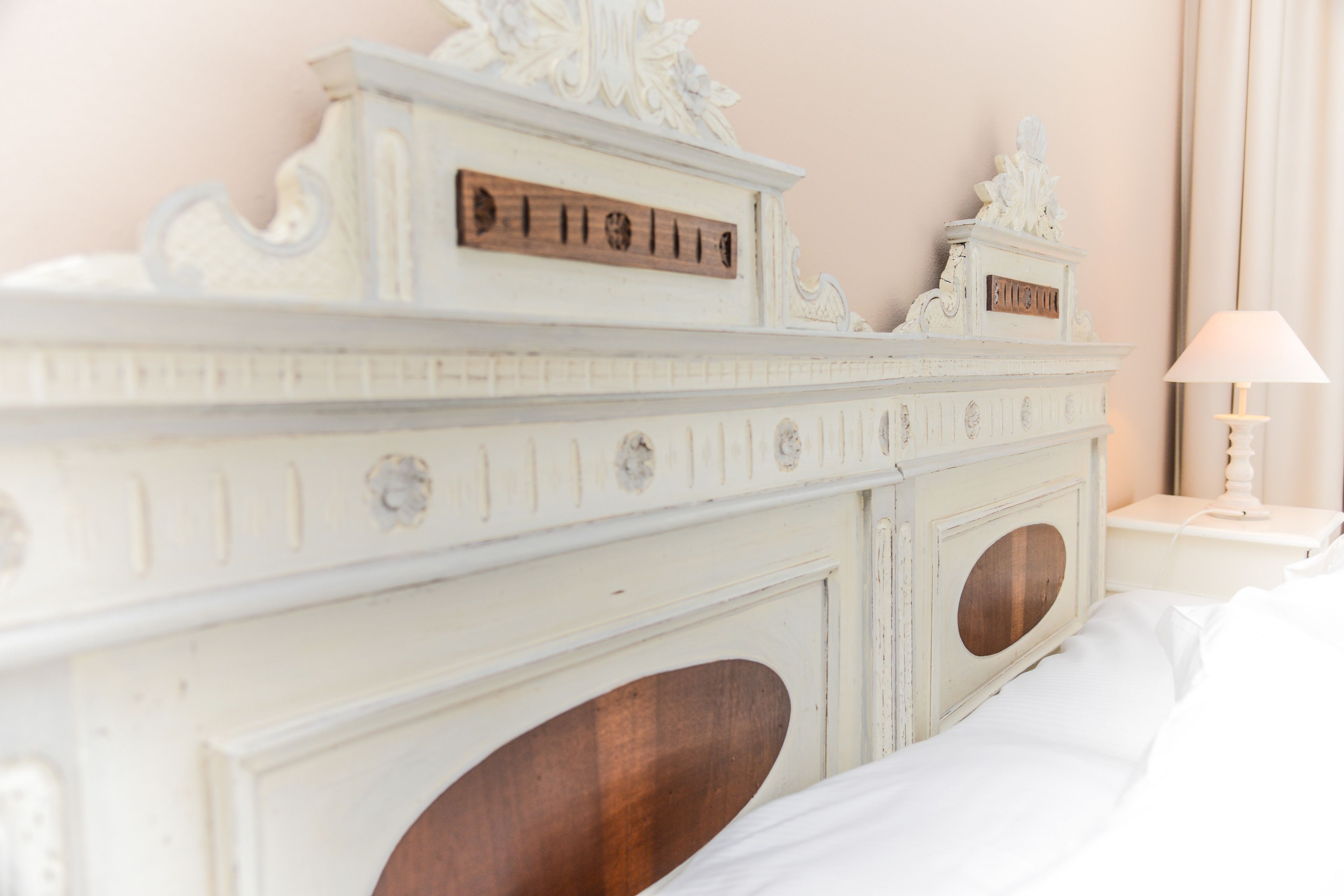 A white, ornate dresser with a mirror and a wooden plaque.