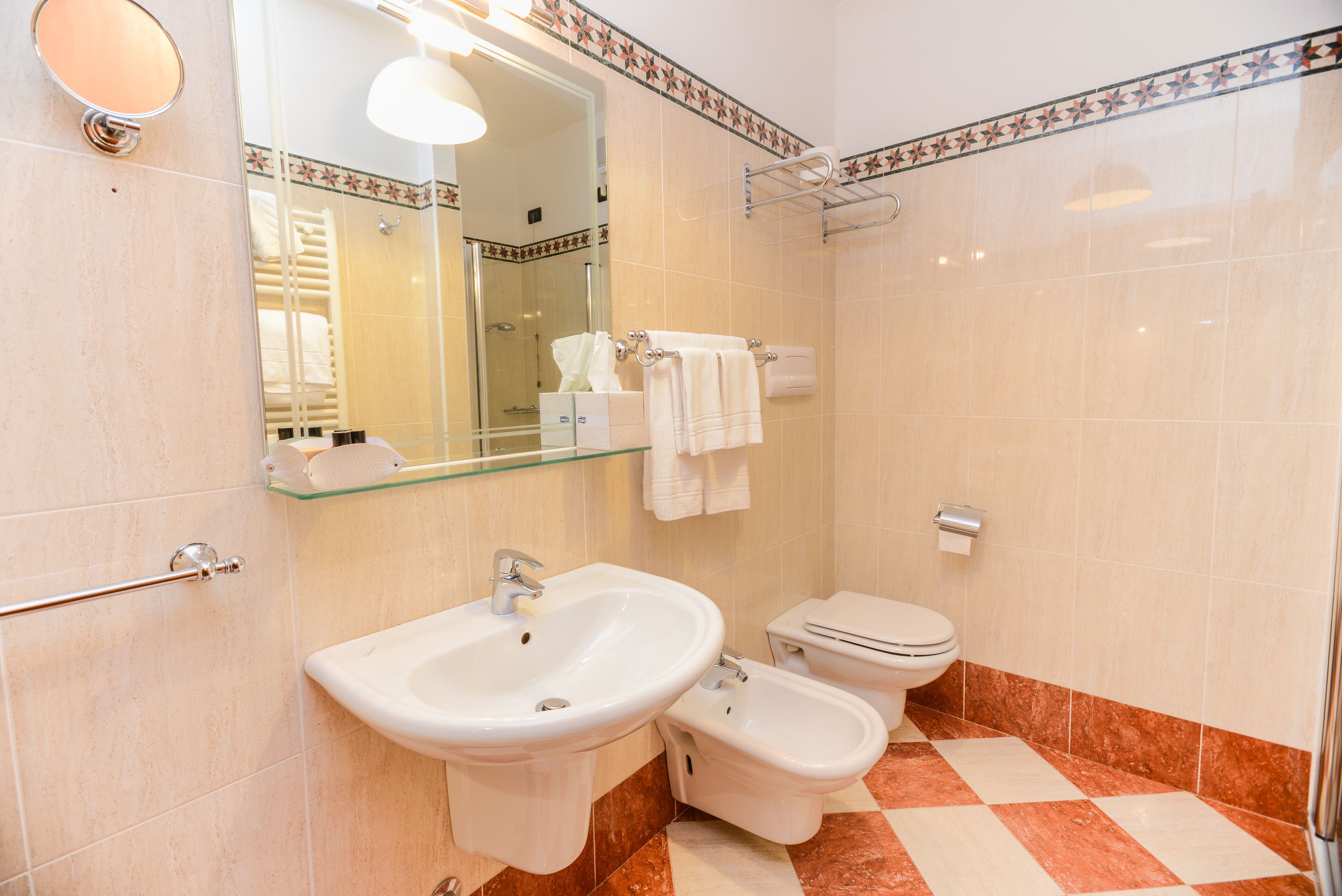 A bathroom with a sink, bidet, toilet, and a glass shower enclosure.
