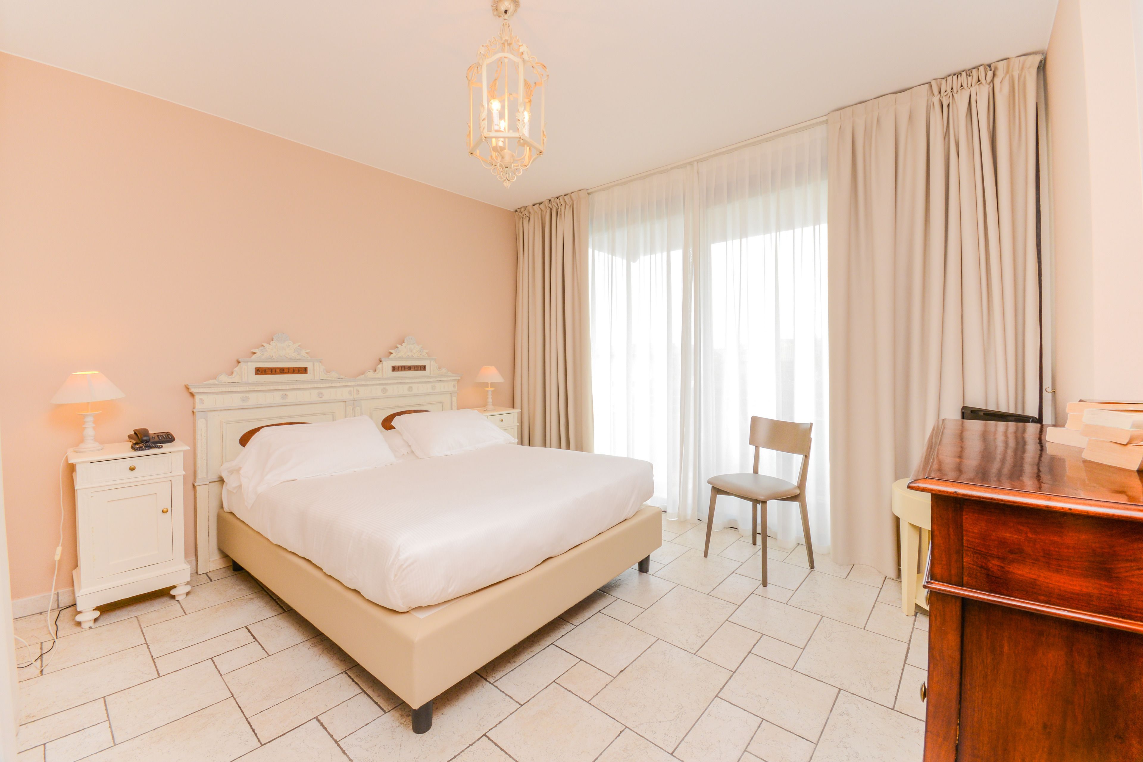 Ein ordentlich eingerichtetes Schlafzimmer mit einem großen Bett, Nachttischen, einem Sessel und einem Schreibtisch.