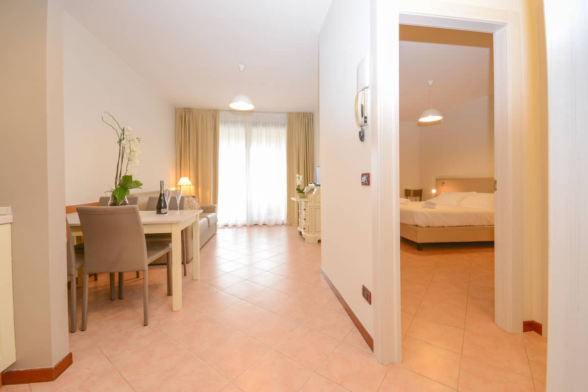 Ein Hotelzimmer mit einem Bett, einem Nachttisch und einem durchgegangenen Türspalt sichtbaren Badezimmer.