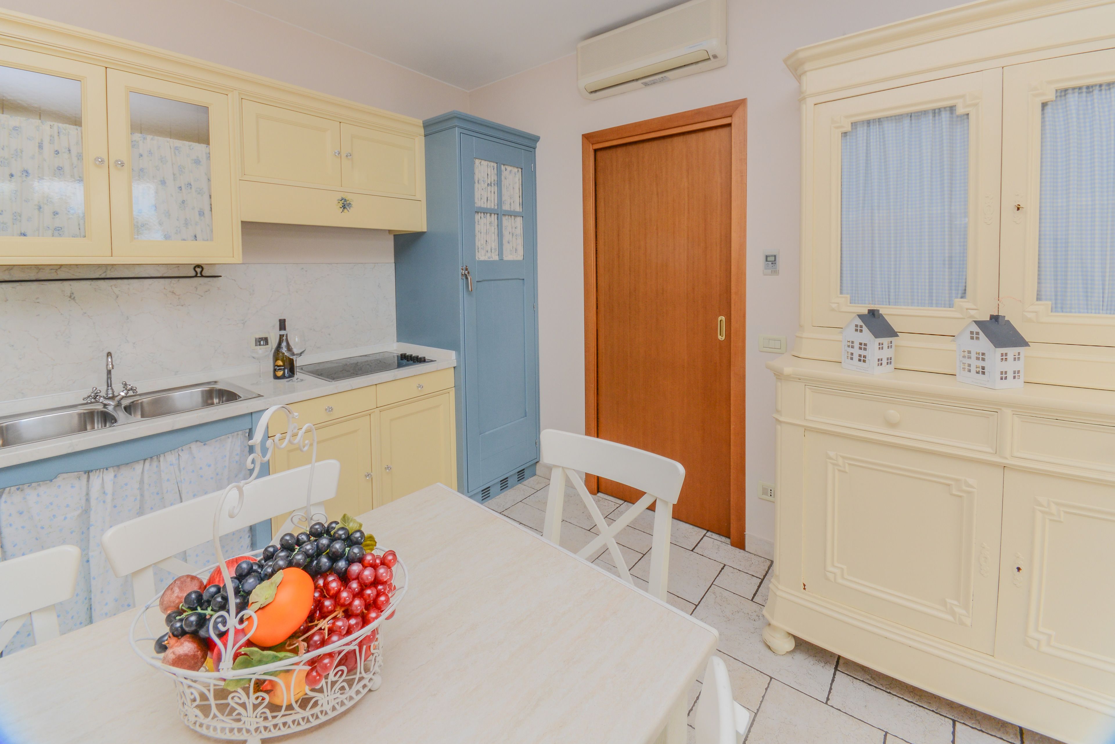 A kitchen with a dining table, a fruit basket, and a sink.