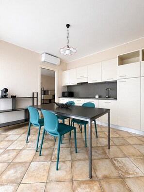 Una cocina moderna con armarios blancos, una encimera negra y una mesa de comedor color turquesa con sillas.