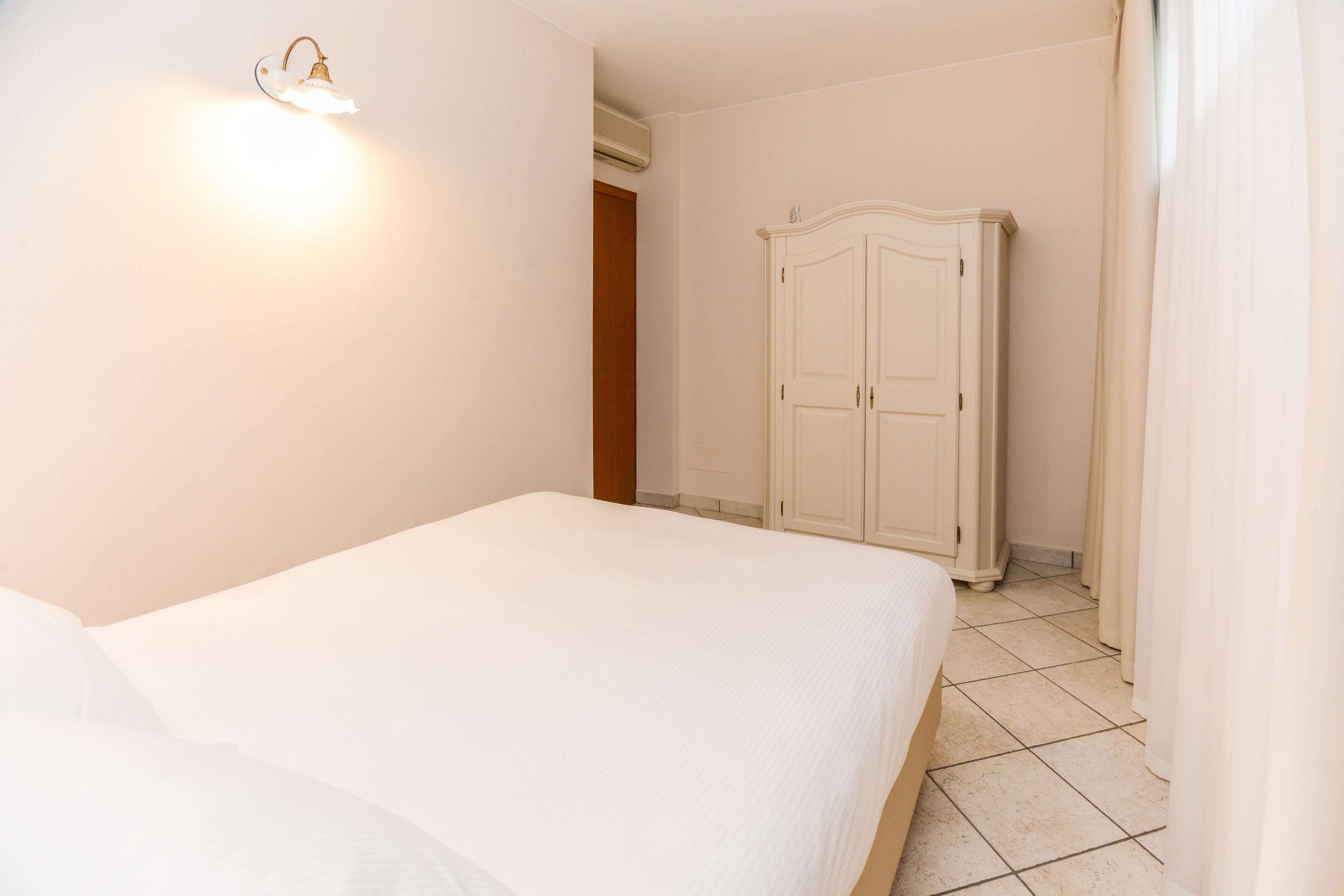 Una camera da letto con un letto, un armadio e una lampada a parete.